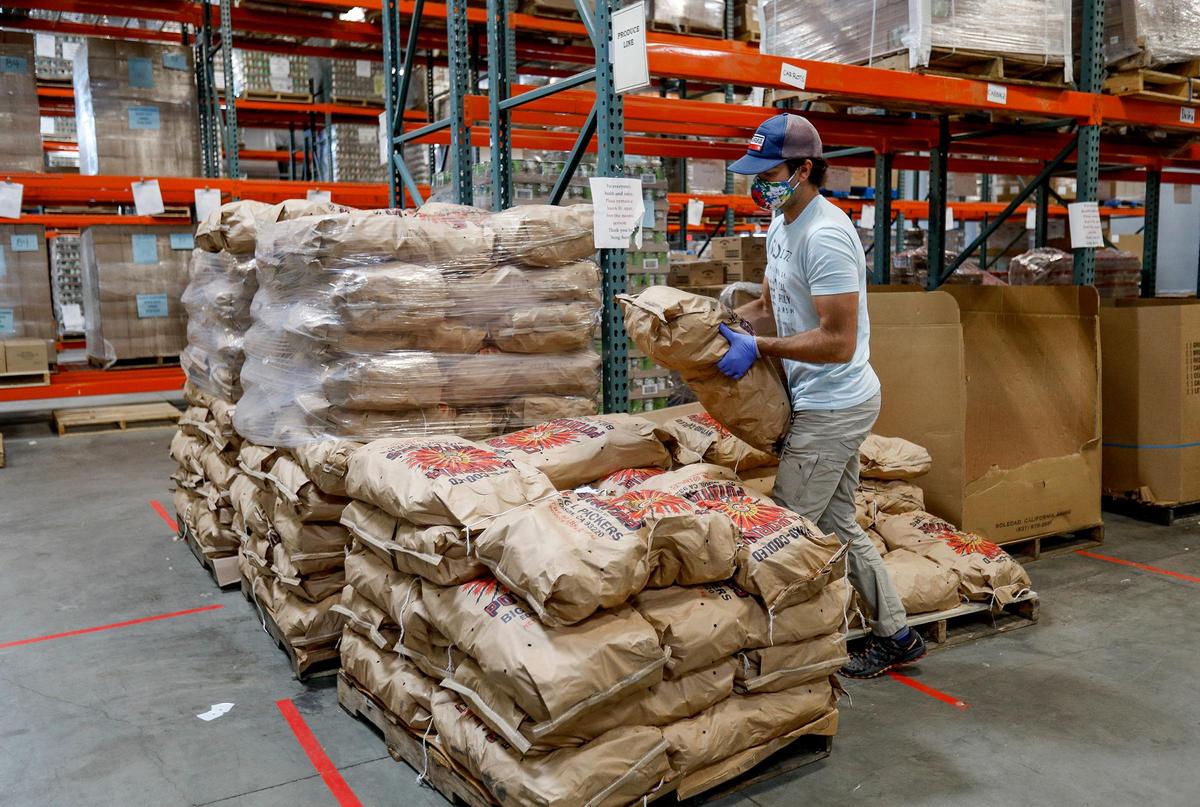 A SLO Food Bank warehouse worker moves sacks of potatoes. SLO Food Bank CEO Garret Olson says demand for the San Luis Obispo County food bank has tripled since the start of the coronavirus pandemic.