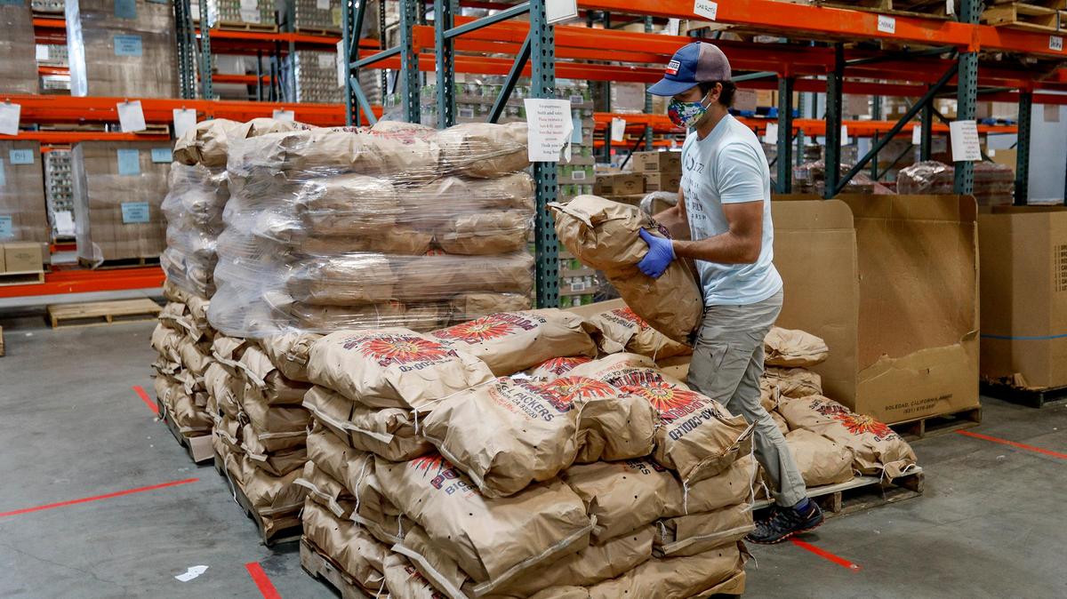 A SLO Food Bank warehouse worker moves sacks of potatoes.