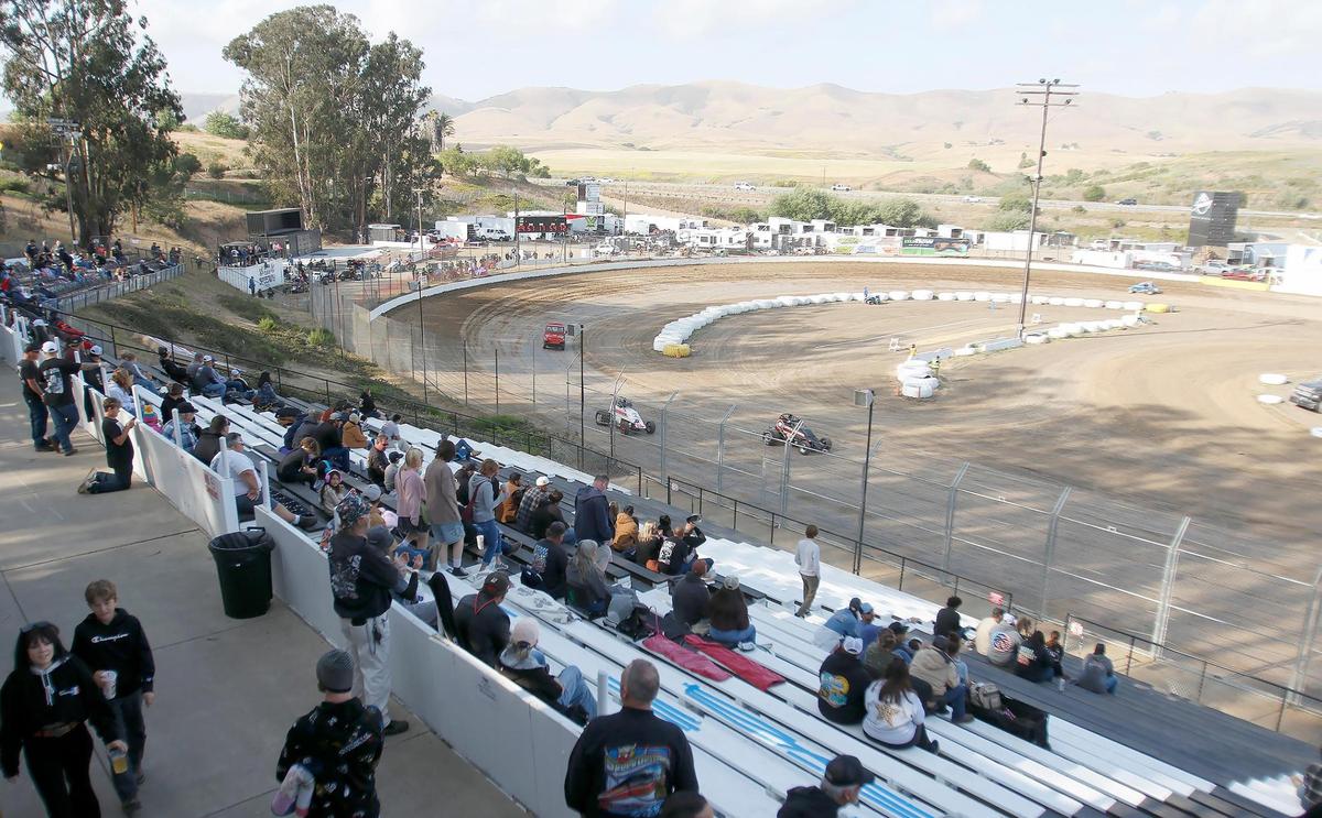 Fans watch a race at the Santa Maria Speedway on May 17, 2025, sitting in the upper rows of the stands to avoid dirt and rocks kicked up by the vehicles.