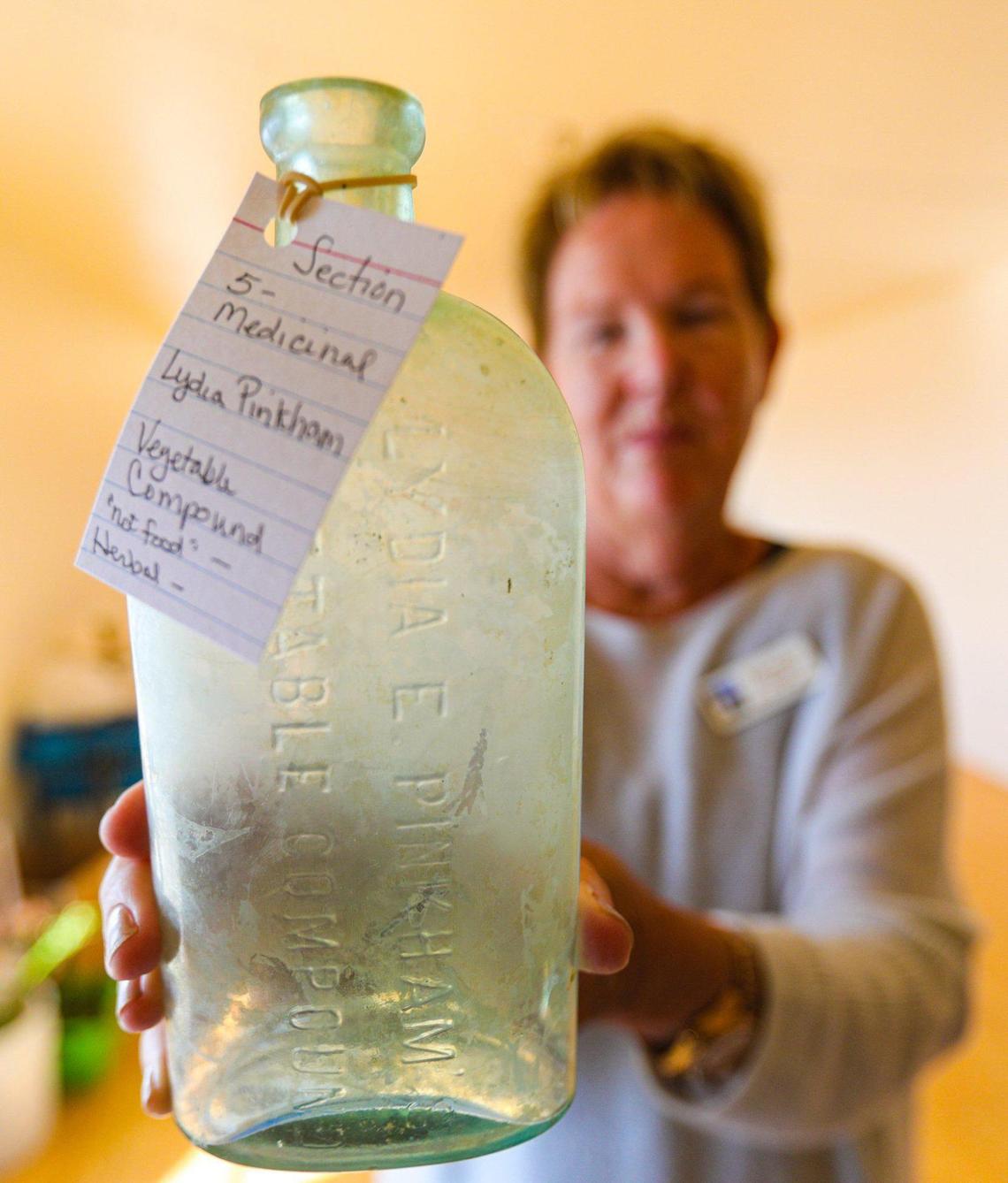 Point San Luis Lighthouse docent Kathy Mastako holds a patent medicine bottle that once held Lydia Pinkham vegetable compound. About 100 bottles collected by U.S. Coast Guard Chief Boatswain’s Mate Richard Guzio in the 1970s from a trash pit at the lighthouse have been returned after five decades and will be displayed.