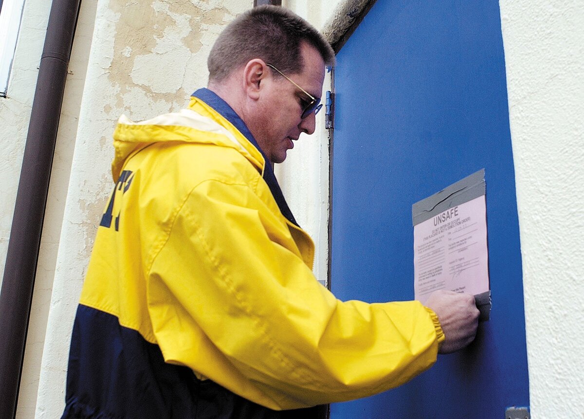 Ashley Lightfoot, director of business operations for Paso Robles Public Schools places a notice on the Flamson Middle School auditorium after the San Simeon Earthquake cracked walls.