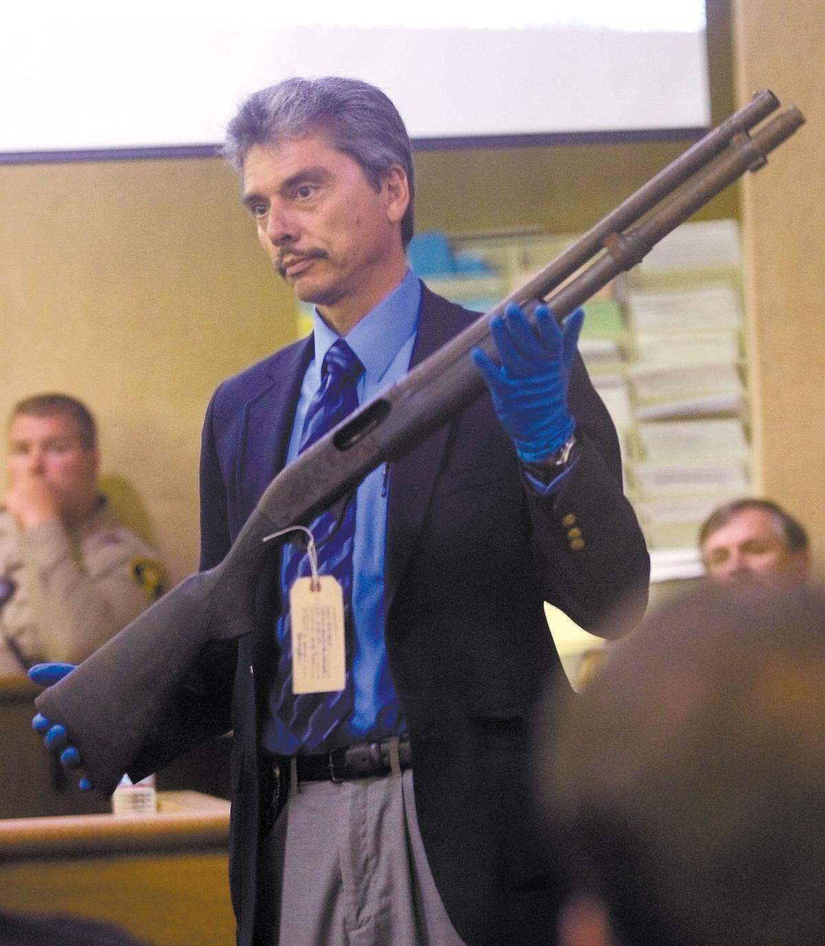 San Luis Obispo police investigator Victor Nunez holds the shotgun that the prosecution says was used to kill Joshua Houlgate of San Luis Obispo. The gun was shown during opening arguments in the trial of Patrick Wollett, 18, and Chad Westbrook, 35, in May. Tribune photo by David Middlecamp