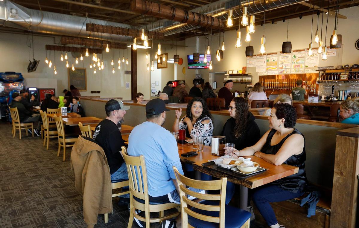 Patrons enjoy food in the brightly lit, inviting dining area inside Wild Fields Brewhouse in Atascadero.