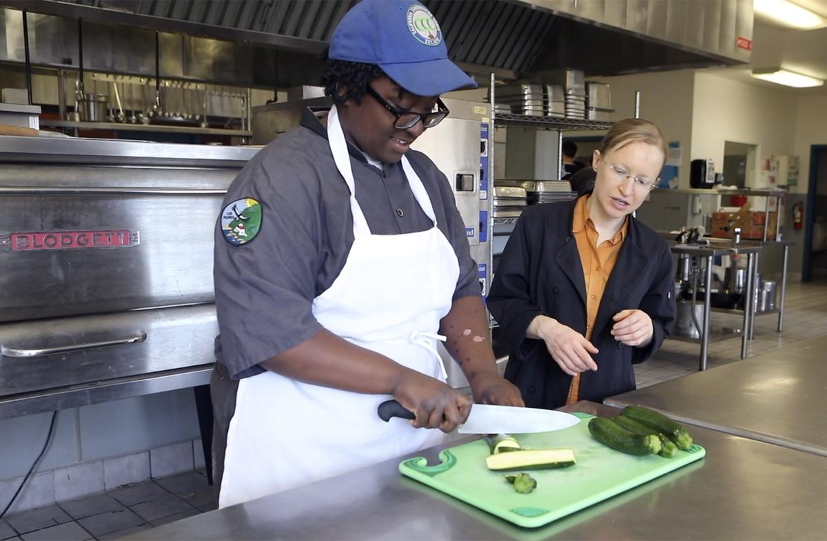 Destiny Joseph of the California Conservation Corps chops veggies as Cuesta College faculty member Elisabeth DeSwart looks on.