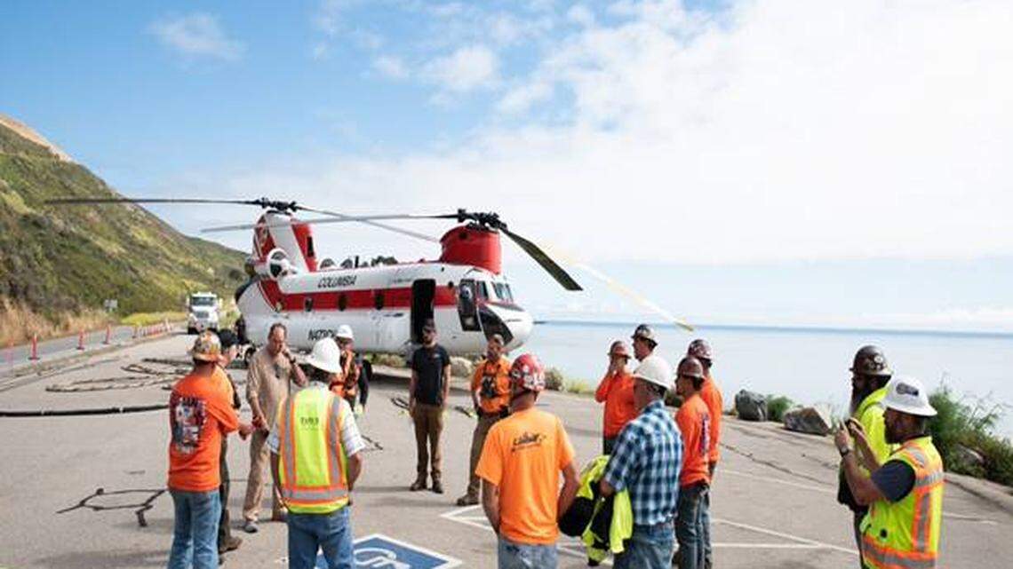 Caltrans crews gather around a helicopter that will carry 25,000 pounds of tunneling equipment at Rat Creek near Big Sur on June 22, 2021.