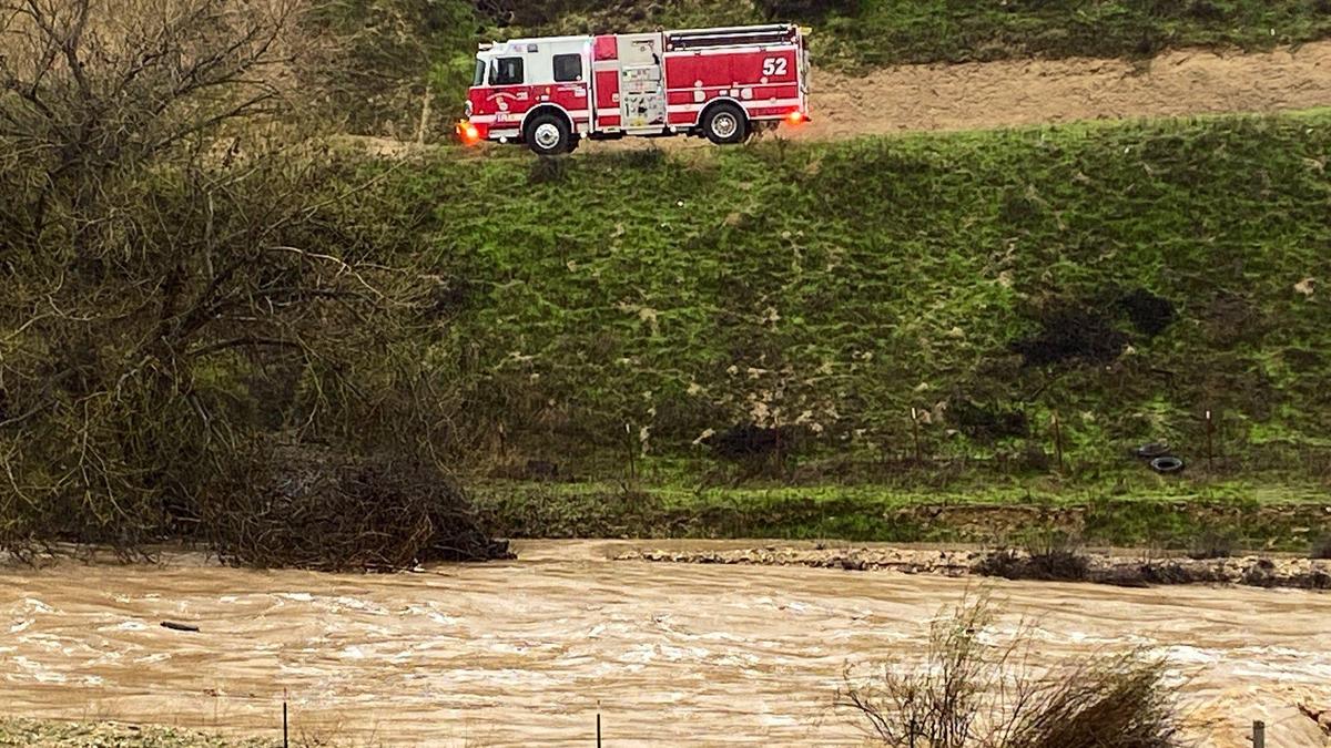 A Cal Fire engine is parked above San Marcos Creek near San Miguel as multiple agencies searched for a missing child who was swept away by floodwaters on Jan. 9, 2023, as another “atmospheric river” storm hit the coast.