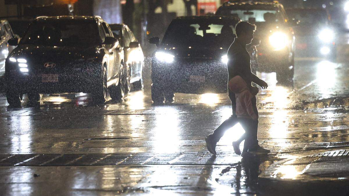 Pedestrians cross Marsh St. as rain falls in downtown San Luis Obispo on the evening of  Feb. 10, 2026. 