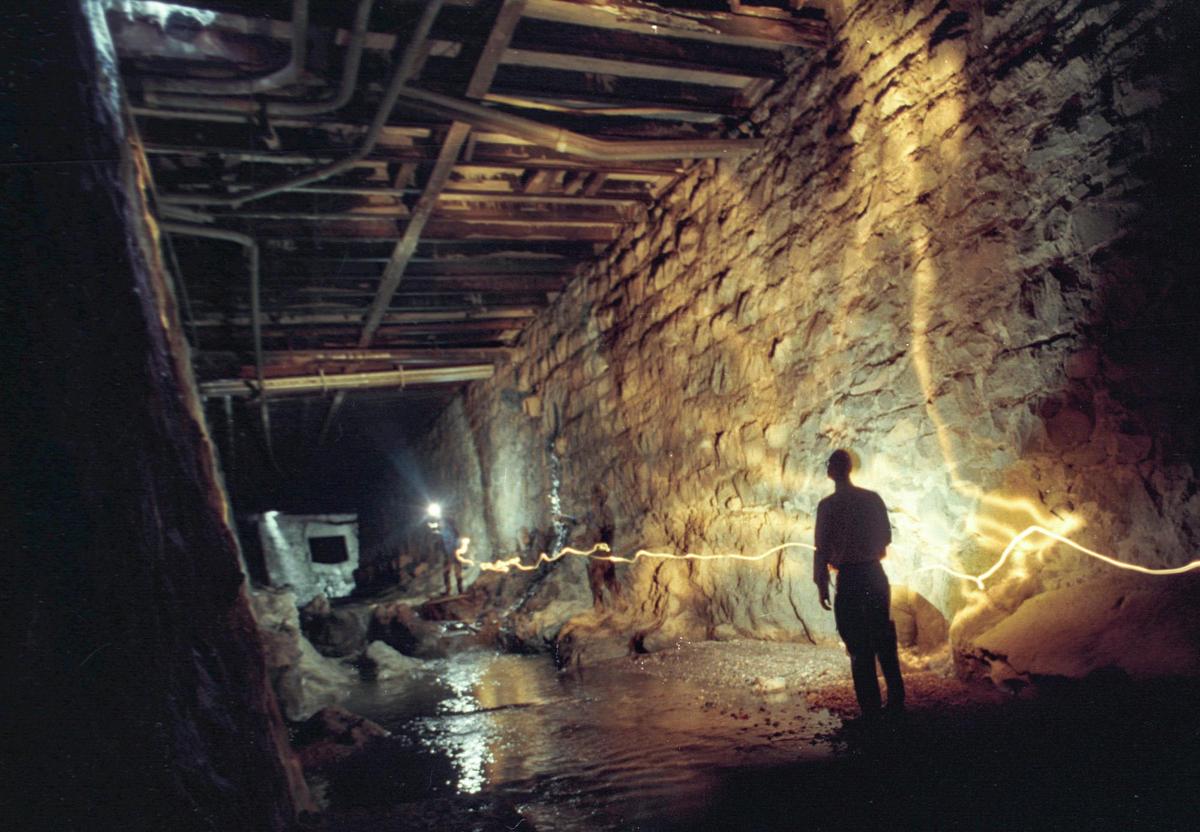 UNDER HIGUERA STREET: Mike McCluskey, SLO City public works director leads a tour where San Luis Creek flows under Higuera street. Bishop Peak granite was quarried to make the walls. The city rebuilt the 87-year old bridge work in 2000-20001. This is a time exposure using flashlights and strobe carried by photographer.