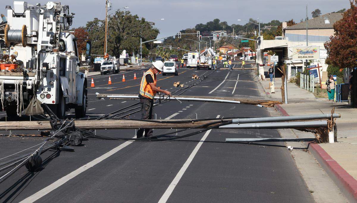 Dan Paradis works to remove hardware from one of at least nine utility poles and lines that were toppled by a truck towing an oversized load on El Camino Real in Atascadero on Monday, Oct. 27, 2025.
