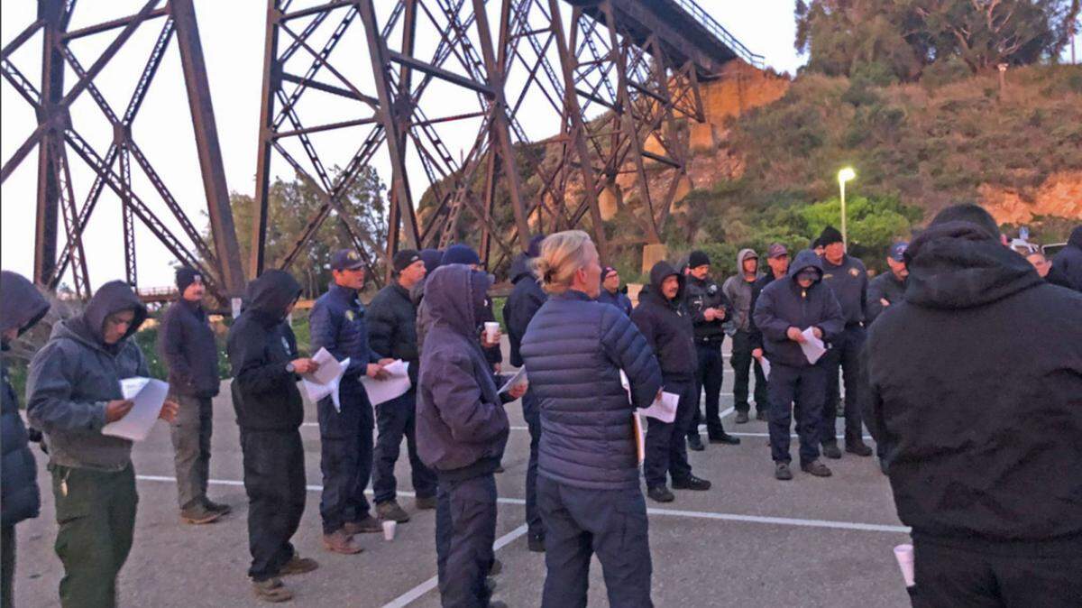 Firefighters assigned to the Hollister Fire listen to a morning briefing on Sunday. The blaze remained at 100 acres, with containment rising to 20% overnight.