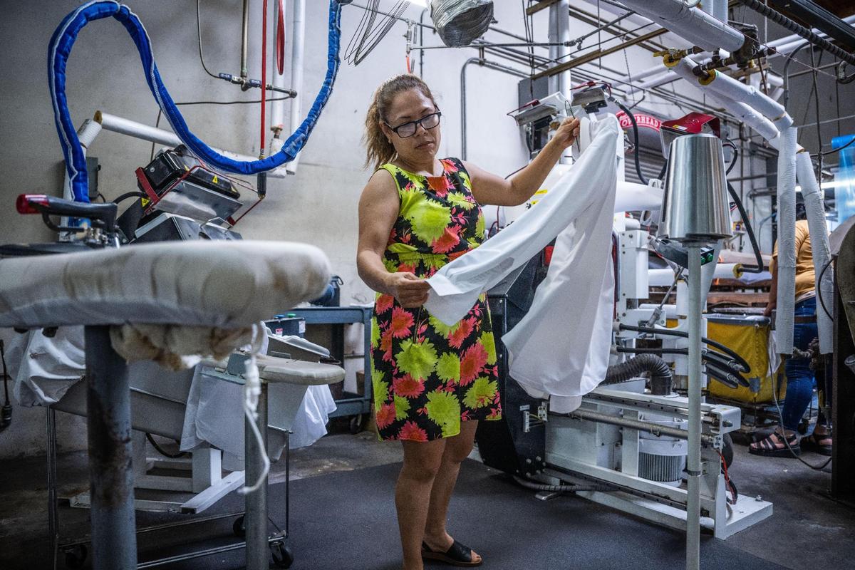 Miriam Alcantar examines a shirt after it was ironed at Prestige Cleaners in Sacramento on Tuesday, July 18, 2023.