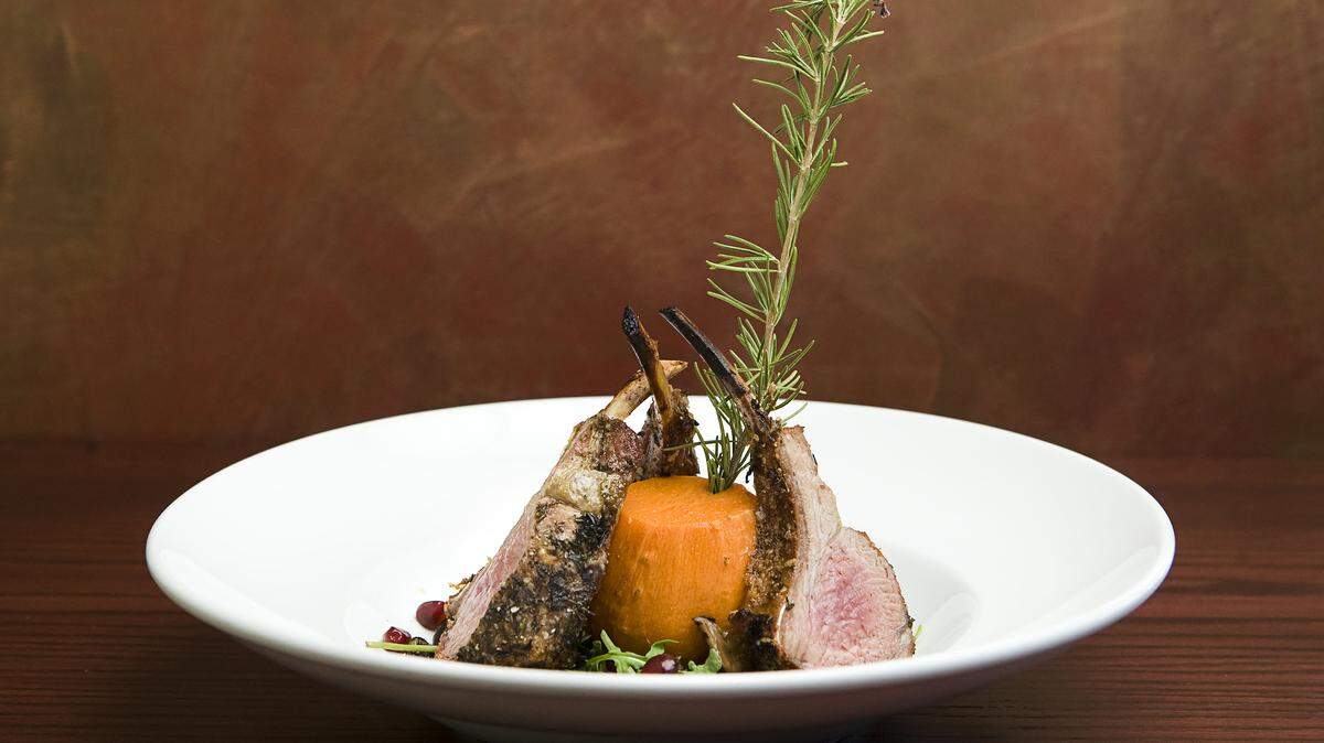 A roasted rack of lamb is served with wild mushrooms, baby arugula and a pomegranate reduction around a chunk of smoked maple roasted yam.