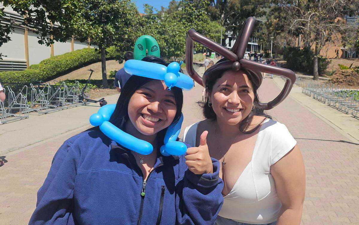 Marisol Salvador, left, and Valeria Garcia Brown, both from Santa Cruz, got balloon hats from Timothy Slater at Cal Poly’s Open House on April 12, 2025.