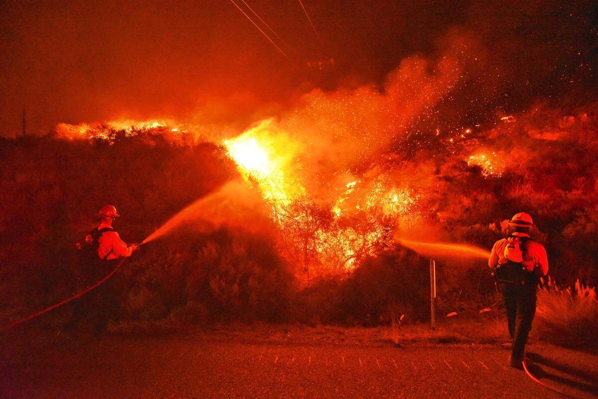 Santa Barbara County Fire Department firefighters knock down flames while standing in the northbound lanes of Highway 101 near Refugio Beach early Tuesday morning. The Alisal Fire had grown to 6,000 acres and was 0% contained as of Tuesday, Oct. 12, 2021.