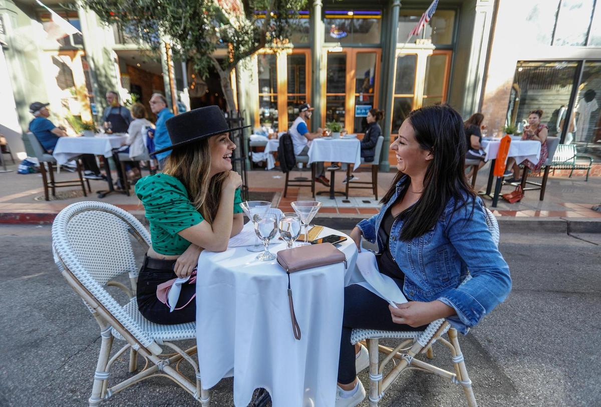 Two friends, Savannah Starr, left, San Luis Obispo and Brooke Smith, Templeton, enjoy street dining in front of Giuseppe’s in San Luis Obispo.. The cities of San Luis Obispo and Paso Robles are taking the dining experience outdoors to help local restaurants and keep citizens safe during the coronavirus pandemic. SLO is closing streets for restaurant tables and Paso Robles set up tables on the grass in City Park.