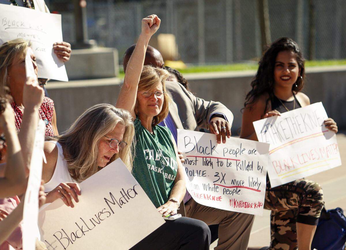 Cal Poly head women's basketball coach Faith Mimnaugh raises her fist alongside students and faculty in the Cal Poly University Union during a 2017 protest against police violence targeting African Americans and other people of color.