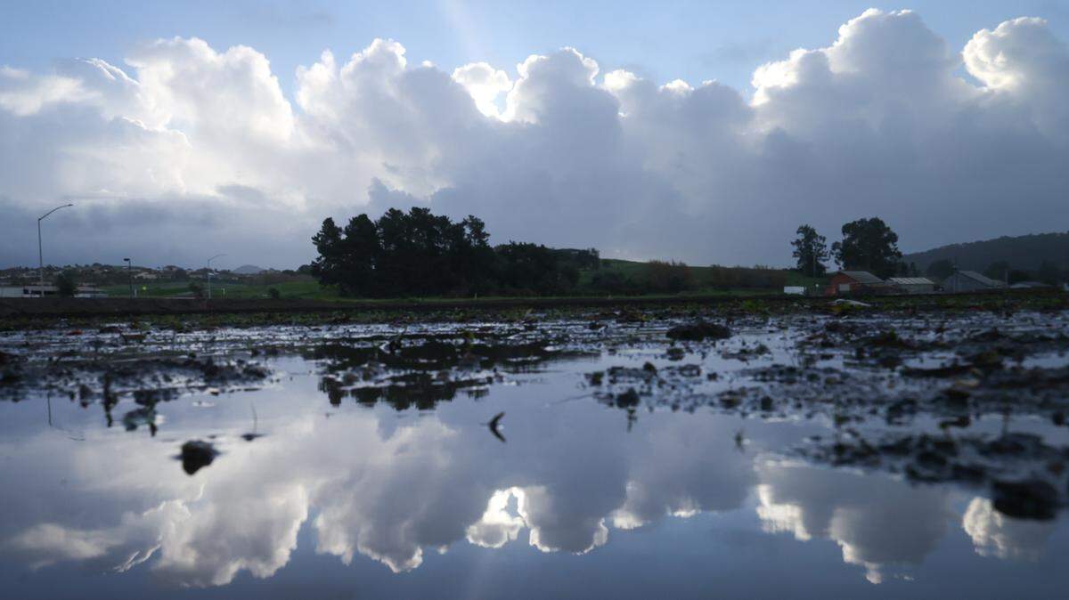 Clouds break in Arroyo Grande near Arroyo Grand High school on Valley Road as rainfall leaves fields filled with water on Thursday, Jan. 5, 2023.