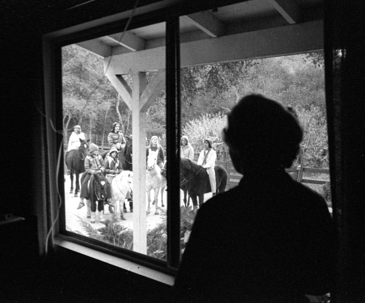Betty Cook of Squire Canyon watches through window as carolers on horseback sing to her Dec. 10, 1976.