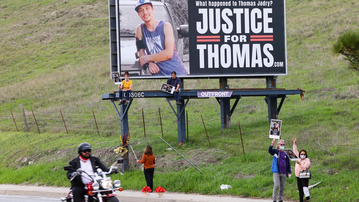 Bill and Mary Jane Jodry, right, attend a demonstration seeking answers in the death of their son, Thomas Jodry, who died in a 2019 fall from the Marsh Street parking garage. Supporters held up placards in front of a billboard on South Higuera Street in San Luis Obispo on Jan. 12, 2022. The billboard sign has since been moved to a new location on the side of Highway 101 at the base of the Cuesta Grade.