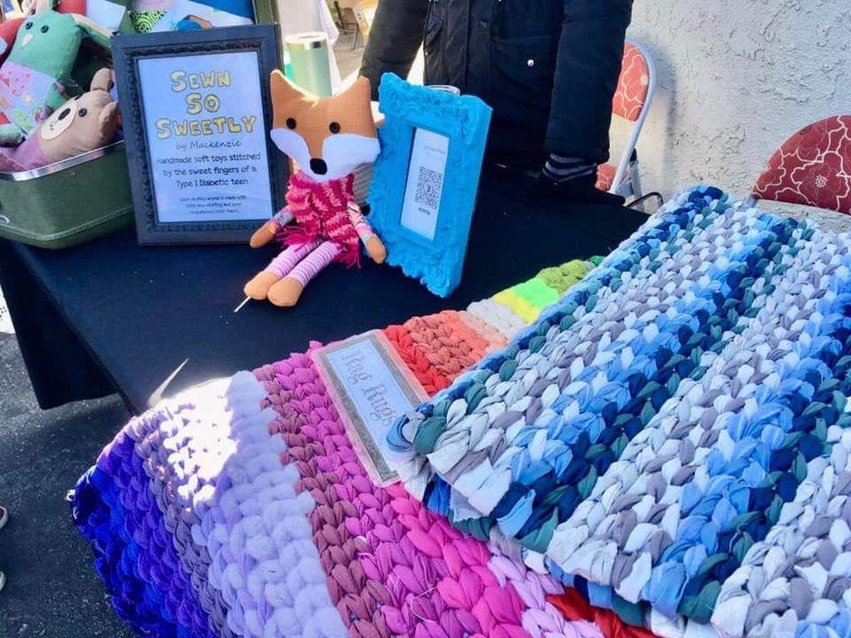 A local vendor table at the Holiday Craft Faire at the Santa Margarita Community Center. Colorful sewn items and a fox sits on the table.