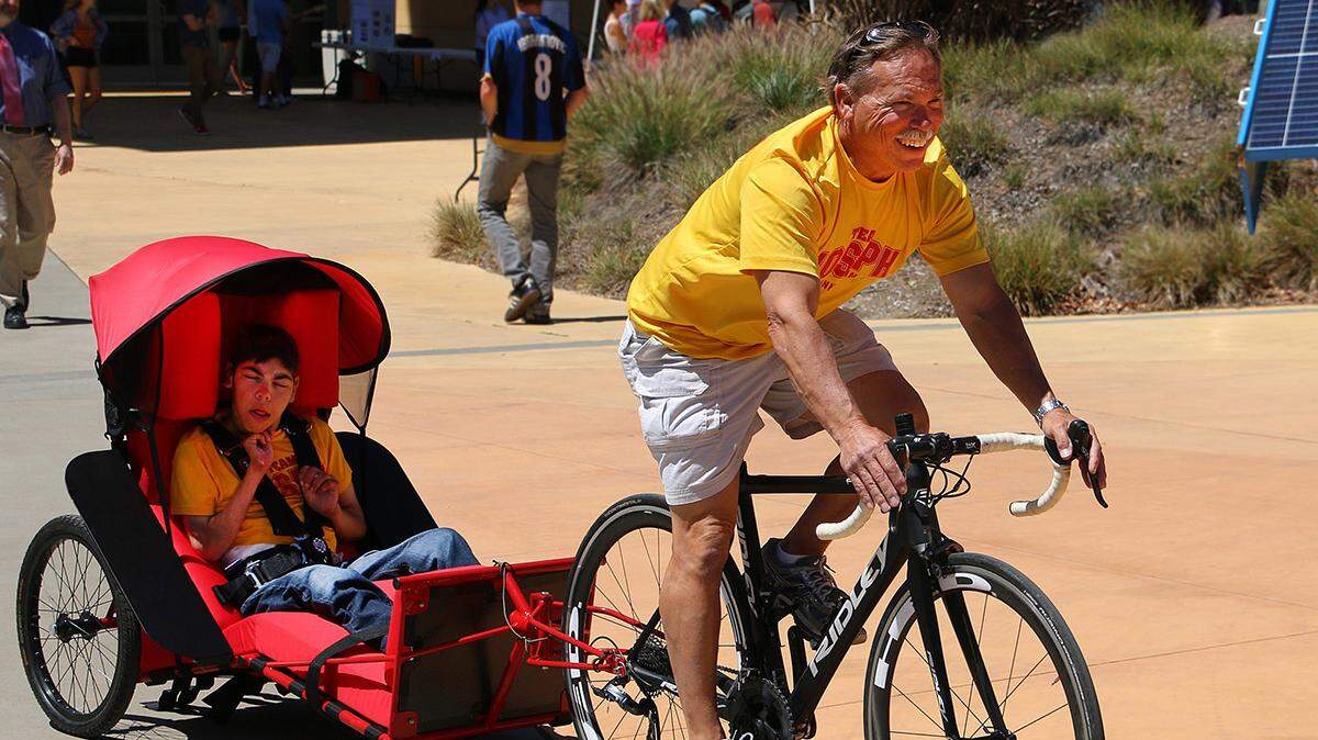 Joseph Cornelius rides in a trailer as his father leads the way on a bike during the Cal Poly Project Expo. The trailer was designed and built by Cal Poly mechanical engineering students. Father and son will participate in the annual SLO Triathlon on Sunday, July 22, 2018.
