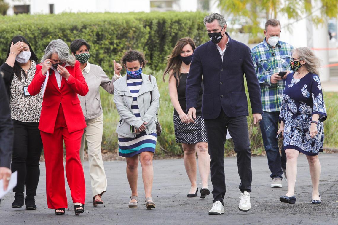 California Gov. Gavin Newsom walks with a group of officials including Heidi Harmon, Dawn Ortiz-Legg, Michelle Shoresman, Lynn Compton and Dr. Penny Borenstein, during his visit to the vaccination site at Cuesta College.
