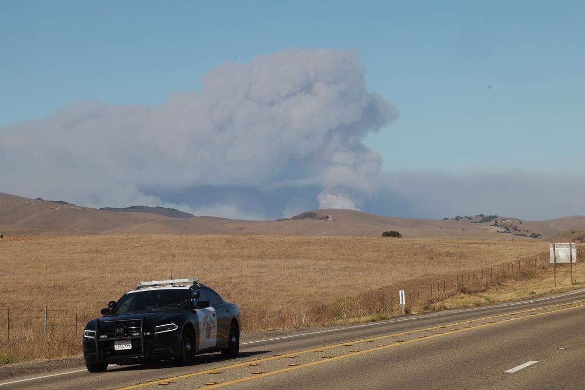 A CHP car sits on Highway 166 east of Highway 101 as the Gifford Fire blazes in the background. The fast-moving fire quickly spread through San Luis Obispo and Santa Barbara counties on Aug. 1, resulting in a highway closure.