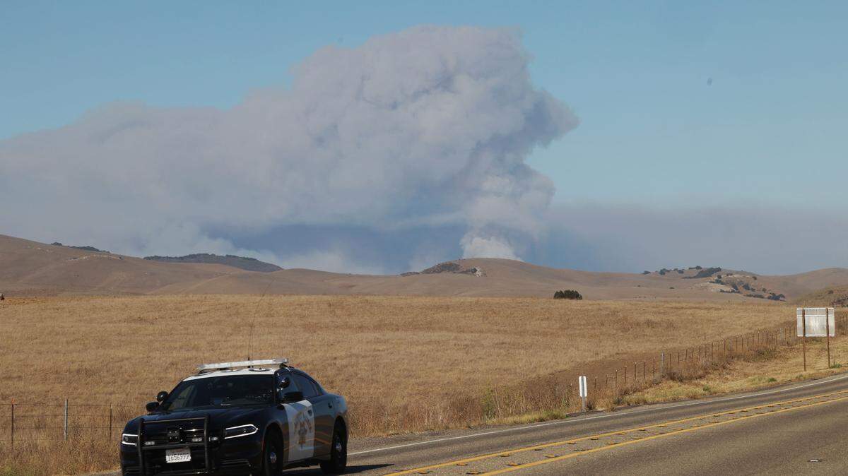 A CHP car sits on Highway 166 east of Highway 101 as the Gifford Fire blazes in the background. The fast-moving fire quickly spread through San Luis Obispo and Santa Barbara Counties on August 1, 2025, resulting in a highway closure.