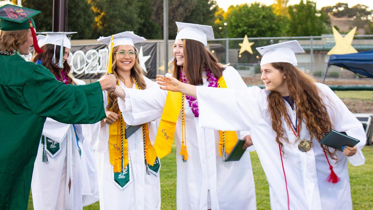 Templeton High School graduates give fist bumps after accepting their diplomas at the school’s graduation ceremony on Thursday evening.