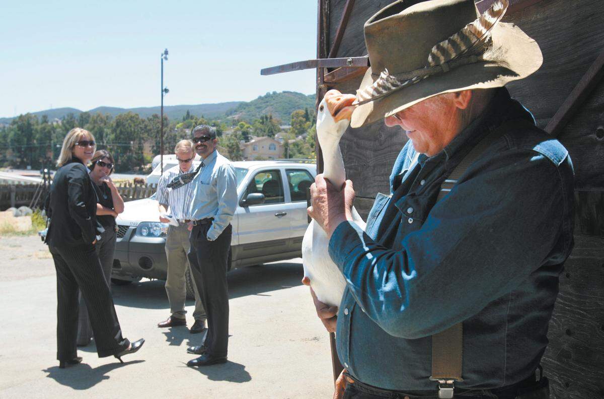 Dan DeVaul provides a light moment as his goose "Aflac" pecks at his hat on July 21, 2008, during a visit from San Luis Obispo County Code Enforcement officers, from left, Jill Bennett, Marie Cowan and Art Trinidade, and DeVaul's attorney John Belsher, third from left, looking down. The goose was a rescue animal from a petting zoo, because it was too aggressive. The officers were documenting the changes on the ranch prior to a nuisance abatement hearing at the Board of Supervisors.