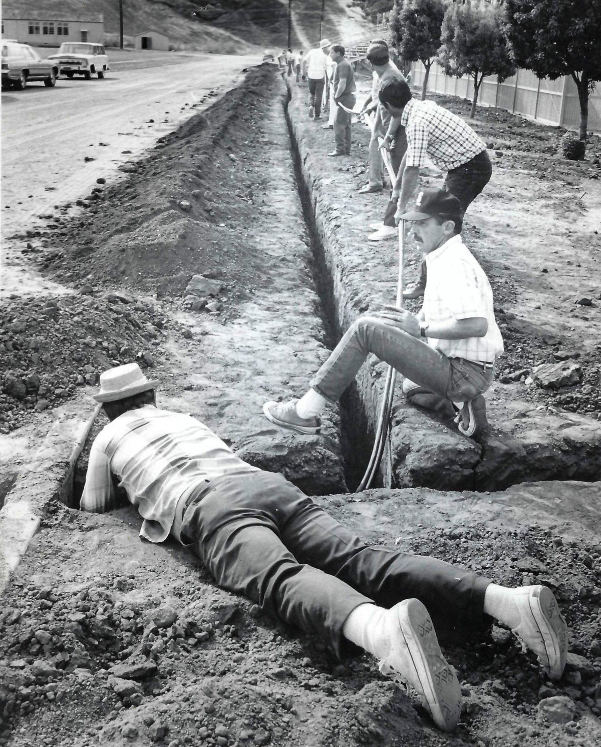 Phil Prijatel, prone, and Rusty DuVal handle the corner turn as the Glack and Gold Club members place the wiring that will provide San Luis Obispo’s Frank Holt Field with lights. Published on Sept. 4, 1971.