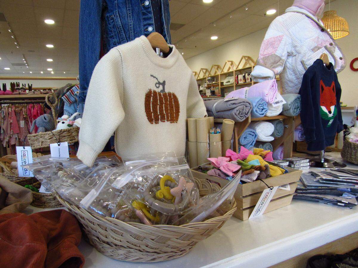 At one of the center tables in Calico Kids, decorated sweaters are surrounded by teethers, puppets and small gifts.
