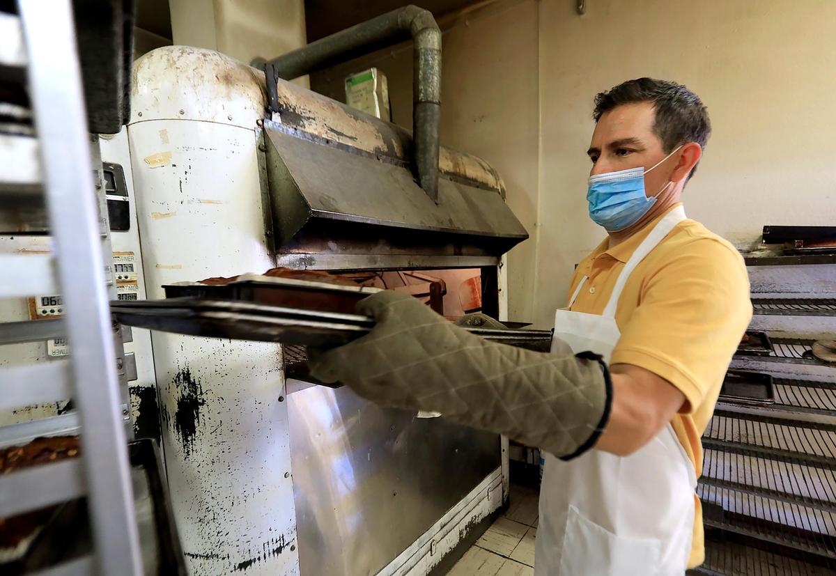 Dante Garcia takes bread out of an oven that’s been in operation since the Carlock family owned Carlock’s Bakery in Los Osos.