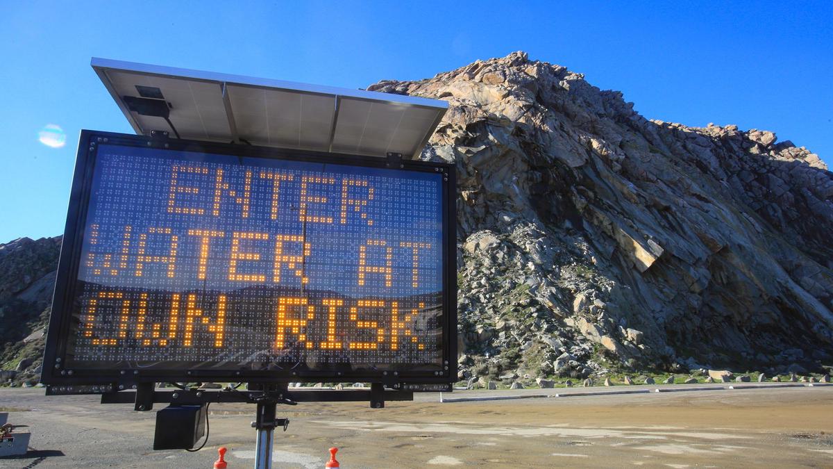 A sign at the Morro Rock parking lot warns visitors about the shark attack on Dec. 24, 2021. Several surfers returned to the water on Tuesday, Dec. 28.
