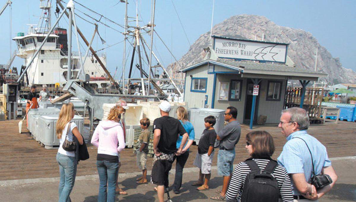 Tourists stop to watch fish being unloaded at the Morro Bay Fishermen’s Wharf.
