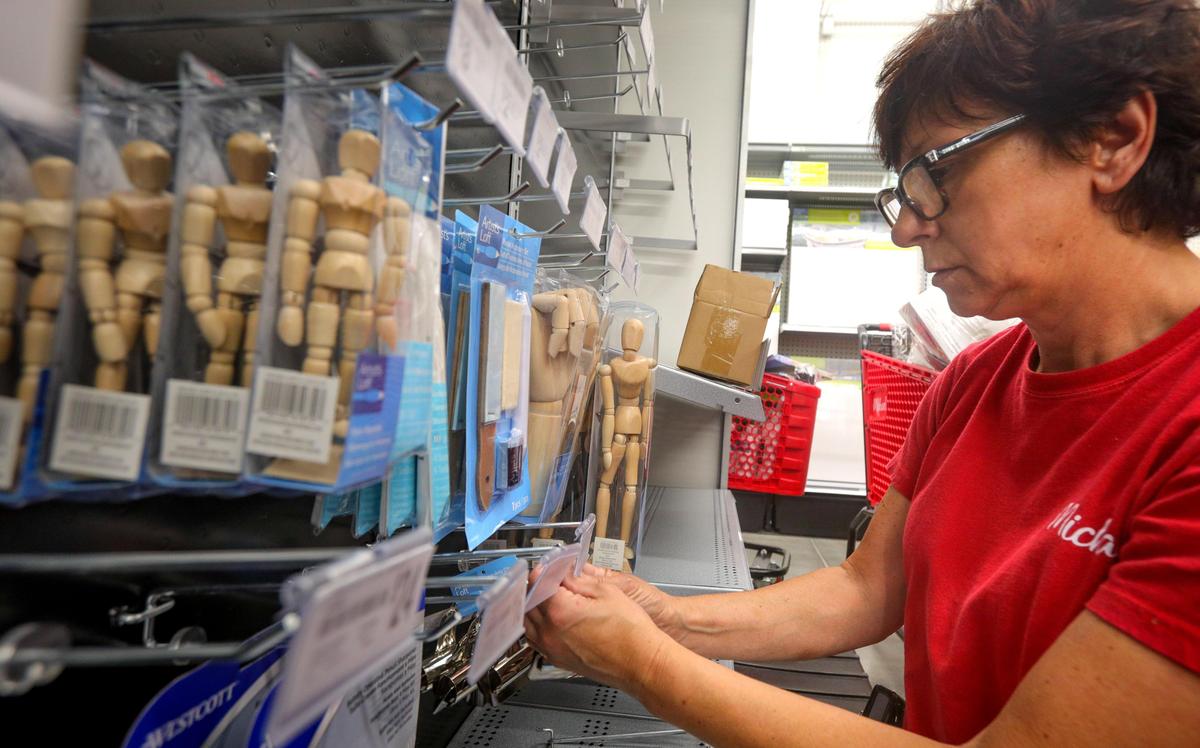 Ann Brown stocks shelves in preparation for the new Michaels opening Aug. 16 in the former Sears building in Madonna Plaza.