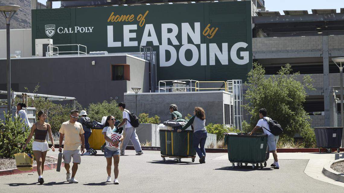 Cal Poly students with the help of other students and family starting to move in for Fall quarter on Sept. 11, 2025. They wheel carts past a banner carrying the school motto, Learn by Doing, on a parking garage.