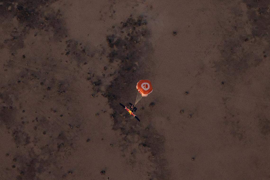 The blue plane parachutes back to earth after Andy Farrington was unable to enter and land it as part of the daredevil plane swap attempted April 24, 2022, in Arizona.