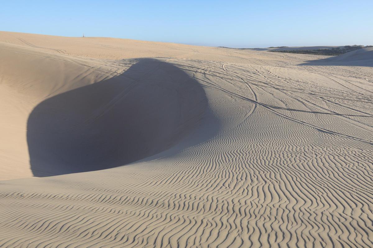 A view of a Witch’s Eye, a swimming pool-sized rift in the sand with deep, steep walls, at the Oceano Dunes in 2019. ATV tracks can be seen in the sand.