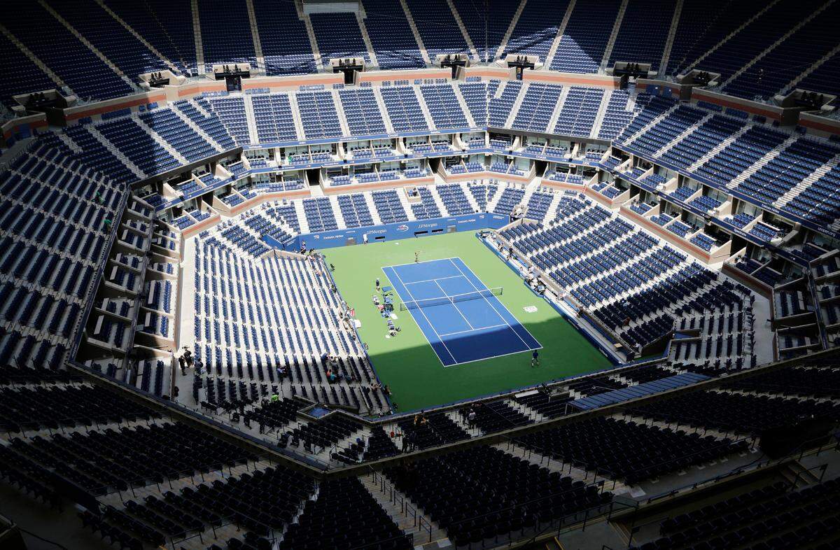 In this Aug. 27, 2017, file photo, players practice for the U.S. Open tennis tournament at Arthur Ashe Stadium in New York. As coronavirus cases spike in other parts of the country before the U.S. Open is supposed to start in New York, the U.S. Tennis Association said Friday, July 31, 2020, that it “continues its plans” to hold its marquee event and another tournament beforehand.