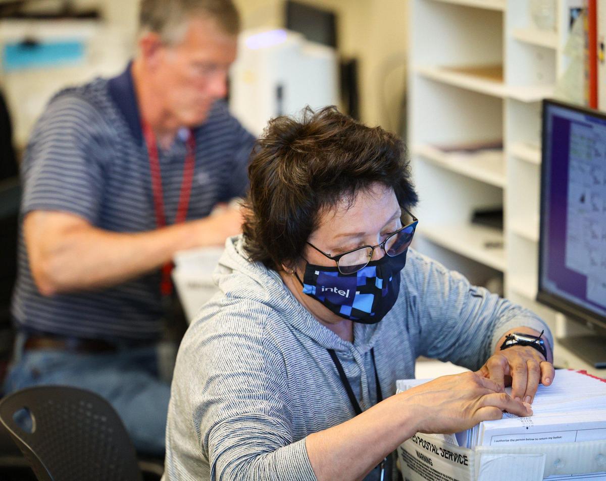 Cindy Tarango verifies signatures on envelopes as one of several cross-checks before ballots are machine-tallied, at the San Luis Obispo County Clerk Recorder’s office on June 14, 2022.