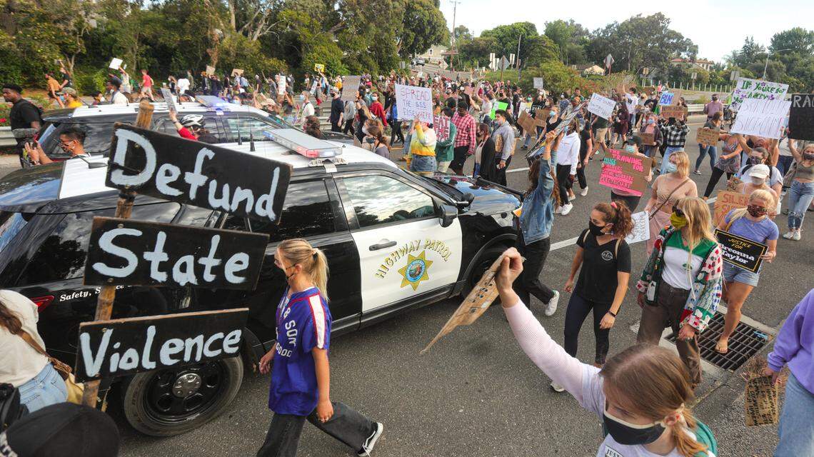 Marchers move past Highway Patrol cars blocking traffic on Highway 101.