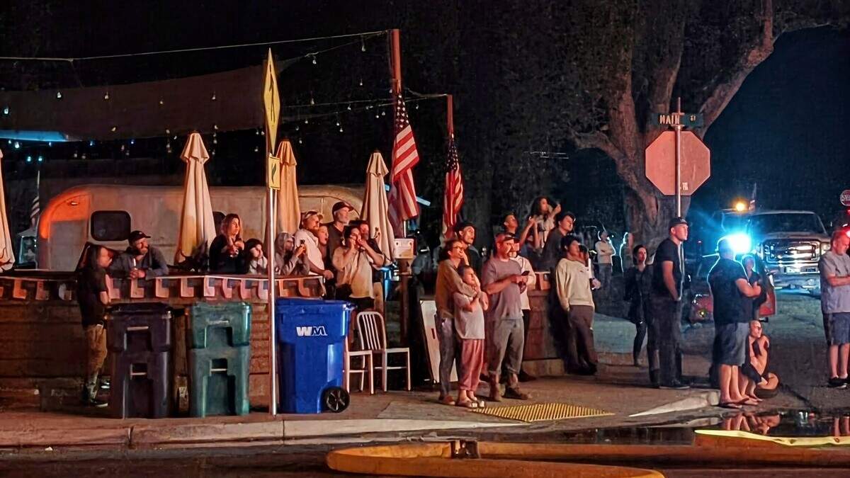 Residents gather near Pig Iron as they watch the Feed & Grain fire during the early morning hours of July 5, 2025. The restaurant became a familiar gathering place for residents as recovery efforts continued in the days that followed.