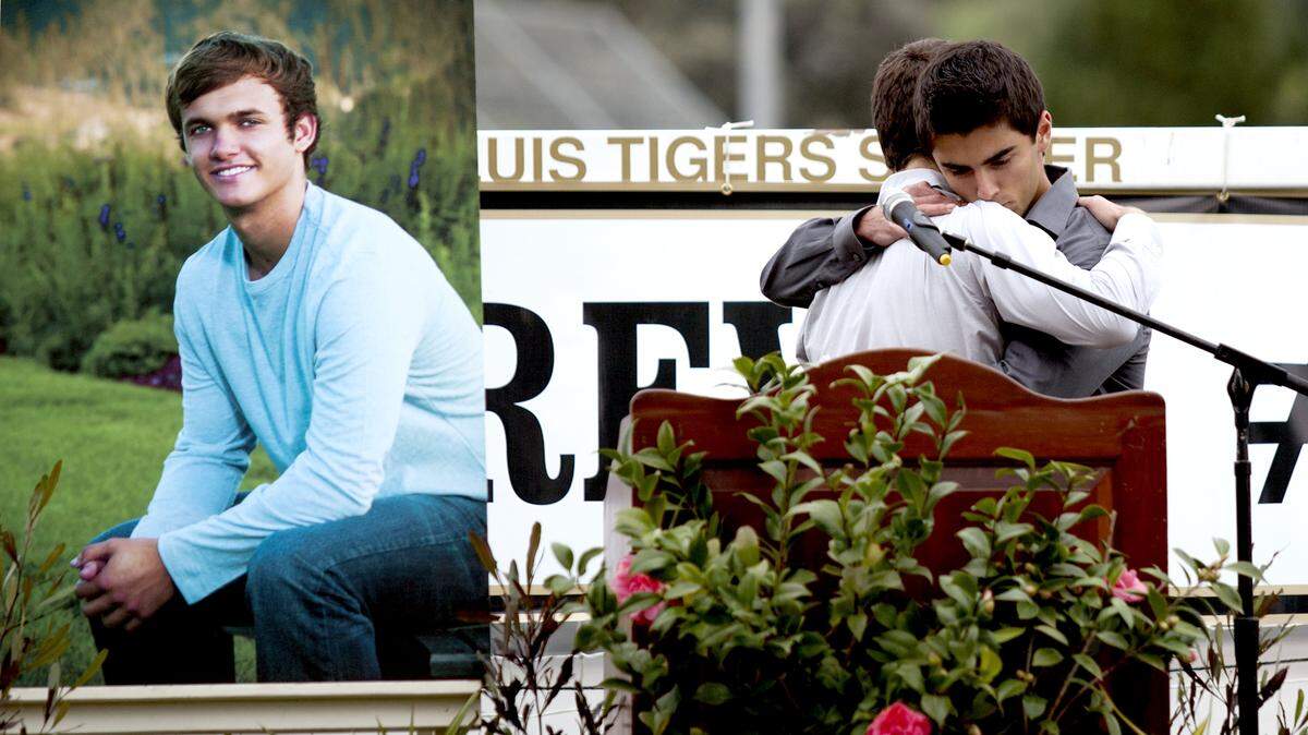 Two of Alex Maier's friends, Kyle Kaminski, left, and Nathan McWhorter hug each other during a service for Maier. They both spoke Saturday during the service at San Luis Obispo High's stadium.