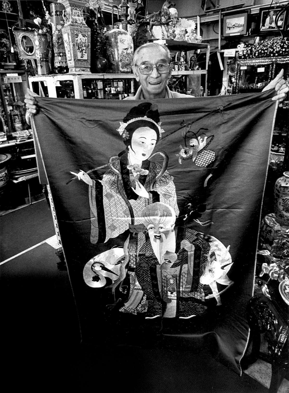 Howard “Toby” Louis, son of Ah Louis, holds a Chinese New Year Banner on Nov. 26, 1992. It is depicting Kwan Yin, Caretaker of prosperity and Shou Hsing, god of Longevity. He is at the historic Ah Louis Store in San Luis Obispo. He was born in 1908, the youngest of eight children.