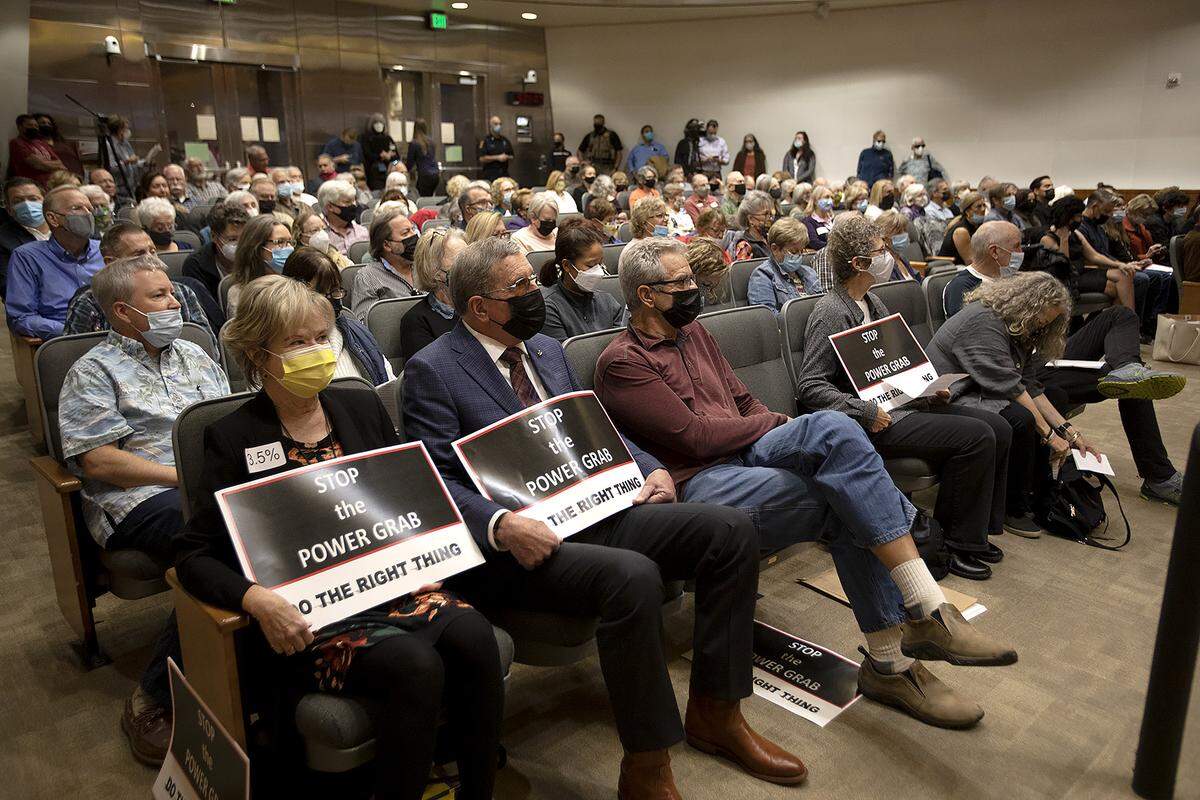 A group of people held signs in the front row. The SLO County Supervisor’s will vote on a redistricting plan for San Luis Obispo County.
