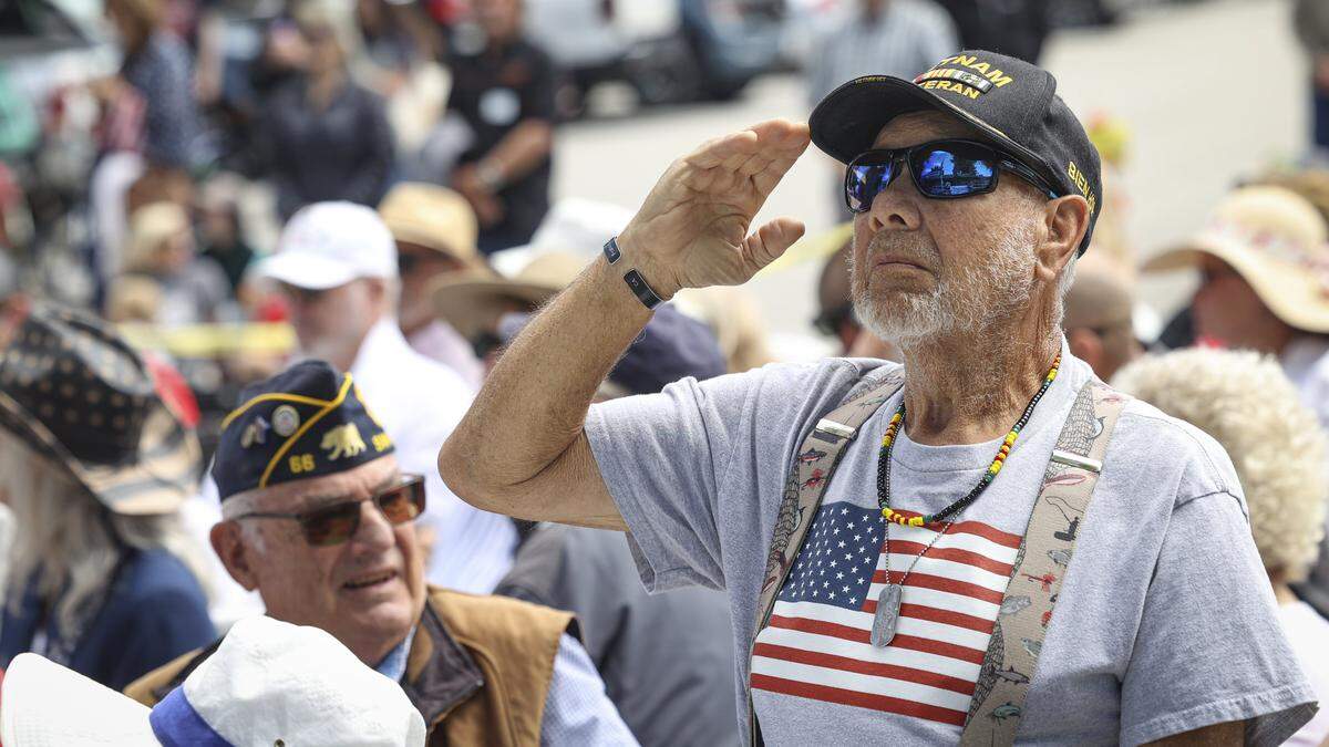 Vietnam veteran Frank Sinay salutes the flag as the U.S. Air Force theme is played by the band. He remembered his cousin, Pete Segundo, who died in Vietnam serving with the U.S. Marine Corps. About 200 people attended the Memorial Day observance held on May 25, 2026, outside the America Legion Post 66 building in San Luis Obispo.
