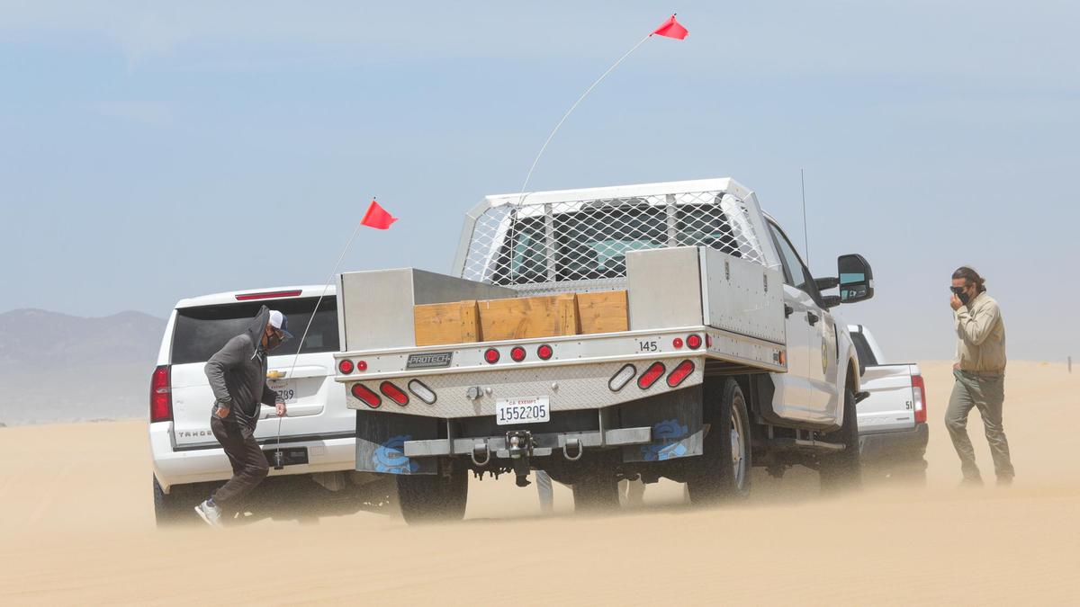 High winds blow sand during a tour of the Oceano Dunes. At left is Karl Tupper, senior air quality scientist with the SLO County Air Pollution Control District, and Alex Velazquez, environmental scientist, with California State Parks, is at right.