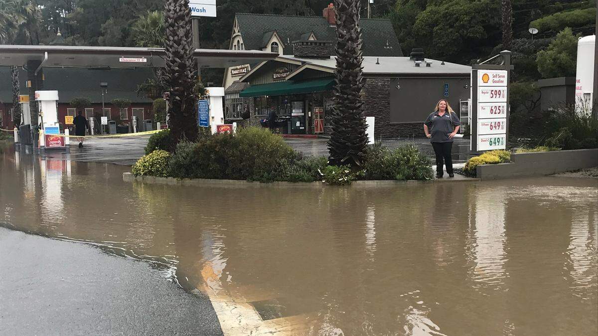 Tammy Hall, assistant manager at Old Cambria Marketplace and Shell Station, surveys flooding in front of the gas station on Main Street on Cambria on Sunday, Jan. 8, 2023.