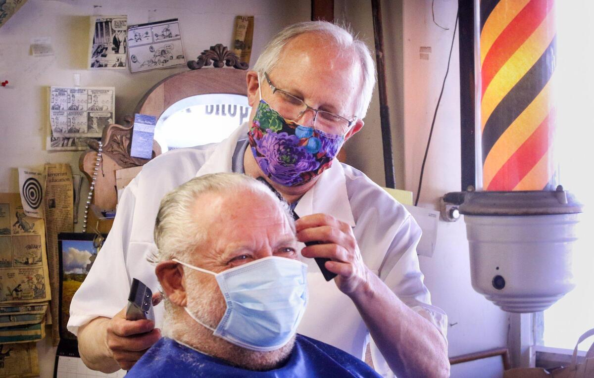 Ray Shearer cuts client Bob Nichols’ hair at the Anderson Barber Shop in San Luis Obispo in May 2020. Customers and staff at salons and barbershops must wear masks under state guidelines.